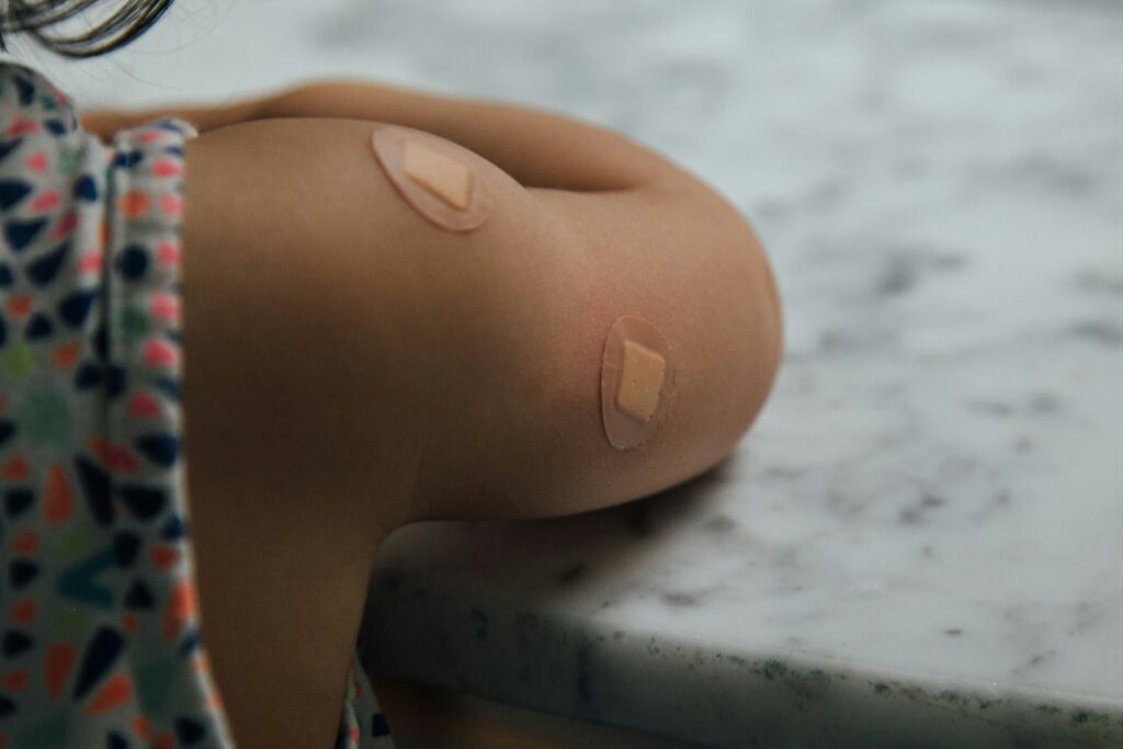 "A child with band-aids on their shoulder and arm, symbolizing recovery and the immunity-boosting properties of the kesar plant."